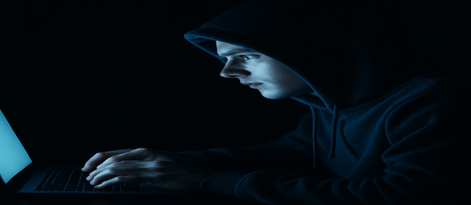 একজন ব্যক্তি অন্ধকার ঘরে ল্যাপটপে 444k ওয়েবসাইটে অনলাইন গেম খেলার ওপর মনোযোগ দিয়েছেন